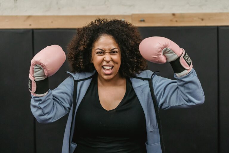 excited young black sportswoman showing biceps after boxing training